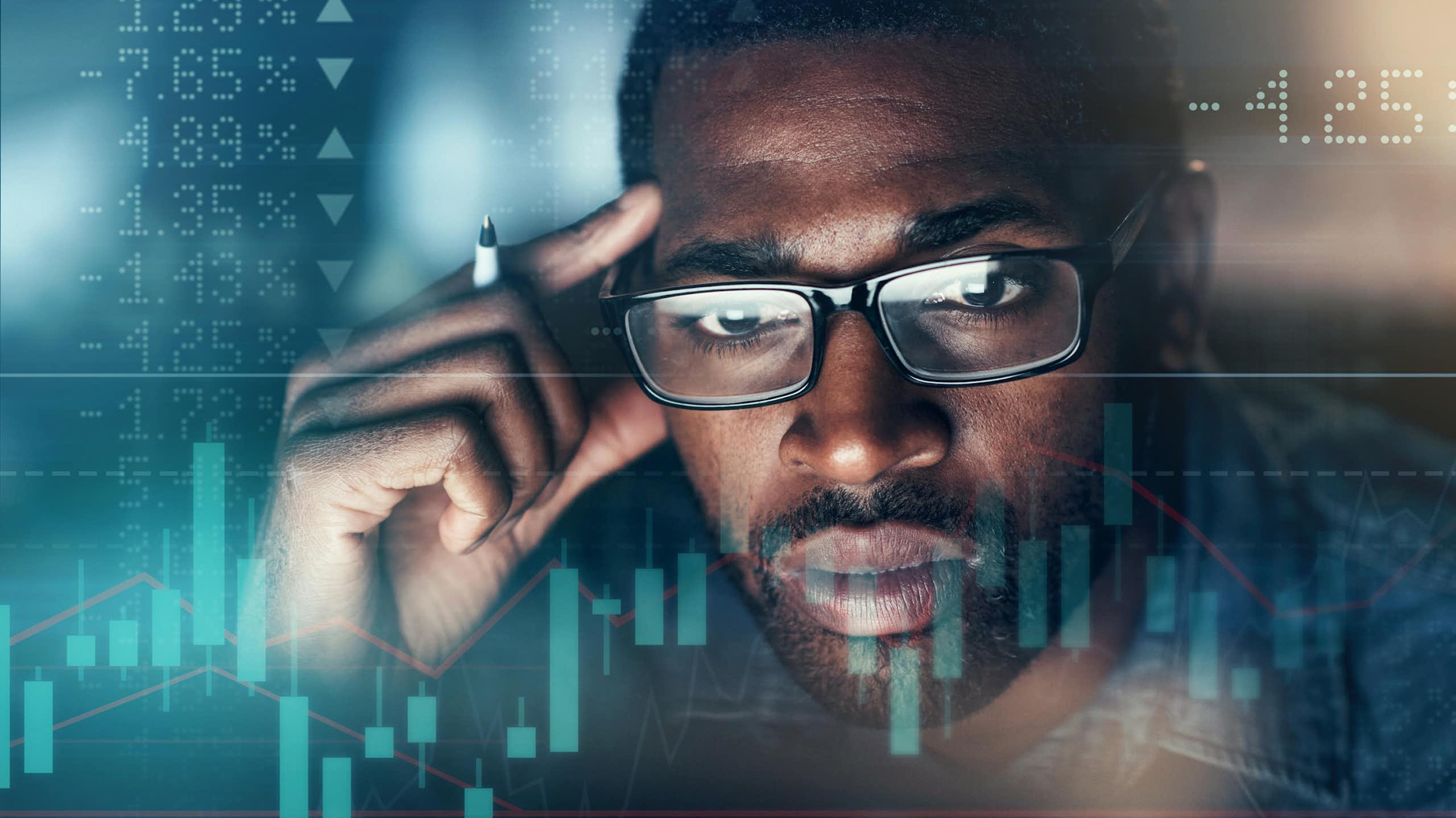 A man stares at numbers and graphs on a screen