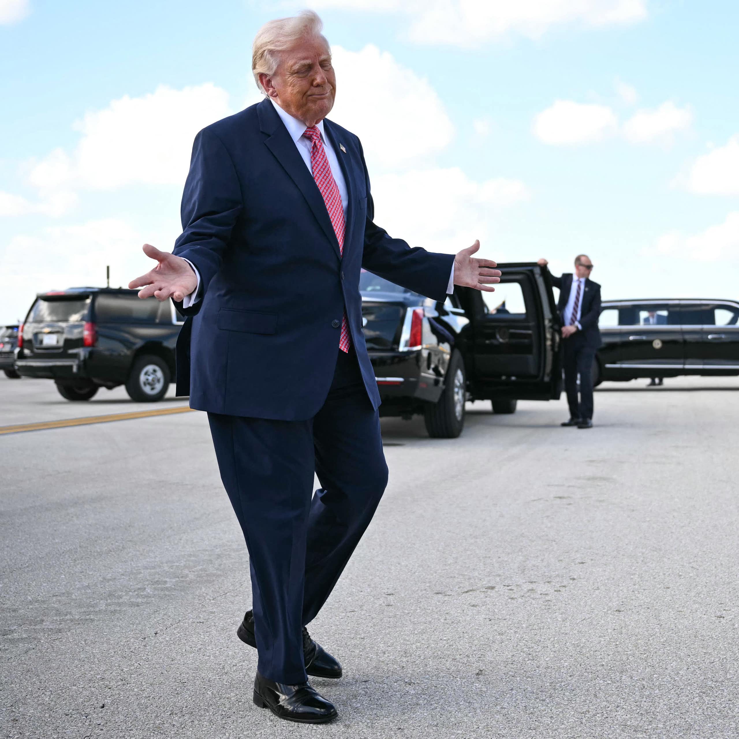 A man in a suit gesticulates with his hands